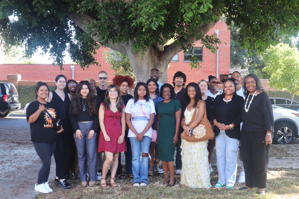 A multiethnic, multi-aged group of people who have received the Biddy Mason Charitable Foundation scholarship are assembled under a tree.